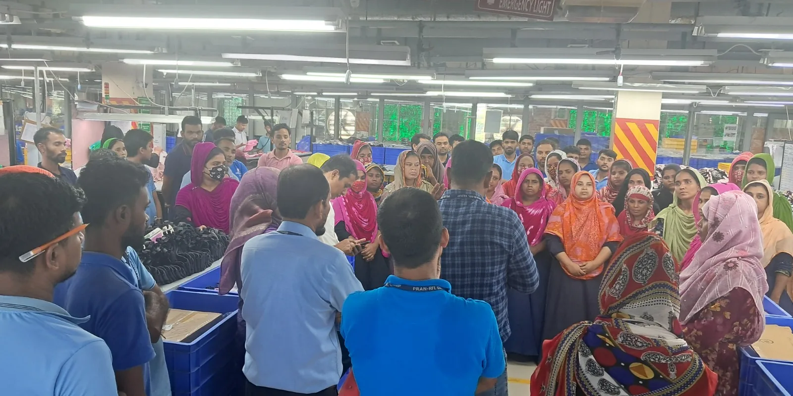 Chum Wellness worker-wellbeing briefing on a Bangladesh garment factory production floor